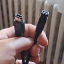 Černý kabel s dvěma různými konektory. Jeden konektor je USB typu B, druhý je vícepinový konektor s osmi kontakty. Kabel i konektory vykazují běžné z…