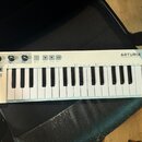 Bílá MIDI klaviatura s 32 klávesami. V pravém horním rohu je nápis ARTURIA a pod ním text YOUR EXPERIENCE. YOUR SOUNDS. V levém horním rohu je modelo…