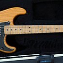 Elektrická kytara typu Stratocaster s přírodním dřevěným povrchem těla a hmatníkem z jasnu. Má černý pickguard, tři snímače (u kobylky humbucker) a b…