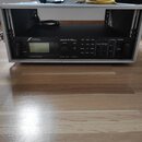 Černý rackový procesor s nápisem FRACTAL AUDIO SYSTEMS a označením Axe-Fx II HD HARMONY PROCESSOR. Zařízení je umístěno v kovovém racku stříbrné barv…