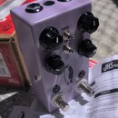 Fialový efekt pedál v kovovém krytu s třemi černými ovládacími knoflíky. Na horní části jsou nápisy CHORUS, SPEED, VIBRATO a VOLUME, dále je zde logo…