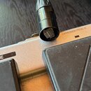 Detailní záběr na stříbrný expresní pedál s černými gumovými plošinkami. Na horní části je nápis EXPRESSION PEDAL B a vlevo nápis ESSION PEDAL A spol…