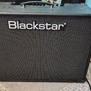 Černý kytarový kombozesilovač s texturovaným povrchem a černou přední maskou. Uprostřed je umístěno bílé logo Blackstar. Nástroj má v horní části čer…