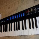 Černá klávesová MIDI kontrolér s bílými a černými klávesami. Na levé straně je nápis ALESIS a vedle něj menší text VORTEX WIRELESS 2. Horní panel obs…