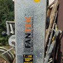 Detail stříbrného kovového profilu s nápisem FANTEK a textem Ferros y Aluminio Navarro S.L. Na objektu je žlutá kulatá kontrolní nálepka s nápisem GE…
