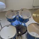 Modrá bicí souprava s bílými membránami. Na několika bubnech je vidět nápis TORNADO a logo IC Music. Souprava zahrnuje basový buben, dva tom-tomy, sn…