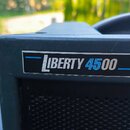 Detailní pohled na horní část černého reproduktoru s mřížkou. Na přední straně je umístěn obdélníkový štítek s nápisem LIBERTY 4500 v bílé a modré ba…