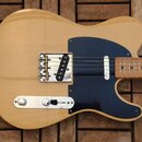 Světlé elektrické kytara s tmele modrým pickguardem a hnedým hmatníkem z javoru. Na snímači je viditelný nápis "Fender Custom Shop". Kovové části, ja…