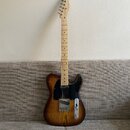 Elektrická kytara typu Telecaster s dřevem s výraznou žilnatostí a tmavě hnědým přechodem k okrajům. Nástroj má černý pickguard, jeden krkový snímač…