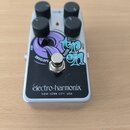Stříbrný efekt pedál s černým předním panelem a čtyřmi černými ovládacími knoflíky. Na panelu je nápis Electro-Harmonix NEW YORK CITY, USA a grafický…