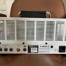 Zadní strana bílého kytarového zesilovače s kovovým šasi a ventilační mřížkou v horní části. Na spodním panelu je nápis ORANGE, model DUAL TERROR a t…