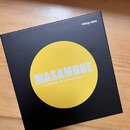 Černá čtvercová krabice s žlutým kruhem uprostřed. V kruhu je bílý nápis MASAMUNE a pod ním menší text —booster & kompressor—. V pravém horním rohu k…