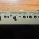 Záběr na zadní panel šedého audio zařízení. Jsou zde nápisy AUDIO IN 2 s popisky VOLUME 2 (MAX MIN) a LINE, AUDIO IN 1 s popisky MIC LINE VOLUME 1 (M…