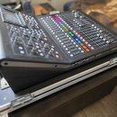Černý digitální mixážní pult s displejem a množstvím posuvníků, knoflíků a barevných tlačítek. Na pravém předním okraku je bílý nápis MIDAS. Zařízení…