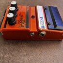 Oranžový efekt pedál s kovovým šasi a černými ovládacími knoflíky. Na horní straně jsou nápisy FX52, CLASSIC FUZZ a popisky VOLUME, TONE, FUZZ. Na pr…