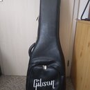 Černý polotvrdý pouzdro na kytaru z materiálu s texturou kůže. V dolní části je bílý nápis Gibson. Pouzdro má zipové uzavírání a přenosný popruh. Pov…
