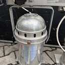 Stříbrný kovový reflektor s oblým vrškem a ventilačními otvory v horní části. Je umístěn pod kovovou konstrukcí, na které jsou nápisy Fixation point,…