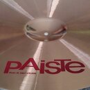 Kovový činel zlatavé barvy s viditelným broušením povrchu. Na spodní části je červený nápis pAiste a pod ním menší text MADE IN SWITZERLAND. Povrch j…