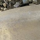 Detailní záběr na povrch kovového činele s viditelnými koncentrickými drážkami. V centru je vyražen nápis „Amati“ a pod ním menším písmem „KRASLICE“.…