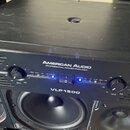 Černý výkonový zesilovač s nápisy AMERICAN AUDIO a PROFESSIONAL POWER AMPLIFIER. Na předním panelu je modelové označení VLP1500, dva ovratové ovládac…