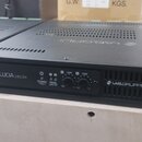 Černý rackový zesilovač s nápisem LUCIA 240/2M a logem LAB.GRUPPEN. Na předním panelu jsou dva ovratové ovládací knoflíky s označením -INF, 0 a -10dB…