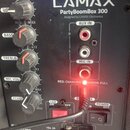 Detailní pohled na ovládací panel černého reproduktoru s nápisy LAMAX, PartyBoomBox 300 a designed by LAMAX Electronics. Panel obsahuje pět otočných…