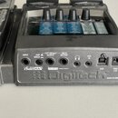 Zadní strana šedého efektového pedálu značky DigTech. Jsou zde vidět konektory INPUT, AMP MIXER, LEFT (Mono) OUTPUT, RIGHT OUTPUT, AUX IN a USB, vstu…