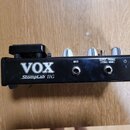 Černý efektový pedál s bílými nápisy VOX a StompLab IIG. Na horní straně jsou tři bílé oválné ovladače, na zadní straně se nacházejí konektory s popi…