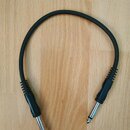 Černý audio kabel s konektory typu jack na obou koncích. Kabel má hladký povrch a u konektorů je opatřen žebrovaným plastovým krytem. Na kabelu ani k…