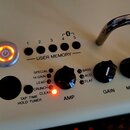 Detail ovládacího panelu kytarového komba v krémové barvě. Panel obsahuje nápisy USER MEMORY s čísly 1 až 5, Bluetooth symbol a tlačítko napájení s o…