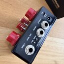 Černý efekt pedál s čtyřmi červenými oválnými knoflíky. Na horní hraně jsou konektory USB a DC 9V. Zadní panel obsahuje tři jack konektory s nápisy I…