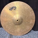Kulatý mosazný činel s viditelným povrchovým opotřebením a drobnými skvrnami. V horní části je černý nápis „Flash CYMBALS“ a v dolní části nápis „16"…
