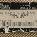 Fotografie detailu identifikačního štítku na černém pozadí. Štítek obsahuje nápisy PEAVEY ELECTRONICS CORPORATION, 711 A STREET MERIDIAN, MS 39301 US…
