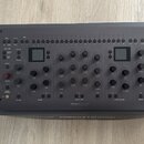 Tmavě šedý kontrolér s nápisem Softube v pravém horním rohu a Console 1 Channel na spodní hraně. Zařízení obsahuje řadu tlačítek, otočných knoflíků a…
