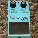 Světle modrý efekt pedál s nápisy RATE, DEPTH, OUTPUT a INPUT. Uprostřed je velký nápis Chorus CE-2 a ve spodní části černý spínací pedál s vyraženým…