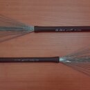 Dvě ks. kovových kartáčů na bicí s hnědými rukojetmi a očkem na konci. Na horním kartáči je nápis vic FIRTH Rymetz HD Sweep. Spodní kartáč má nápis v…