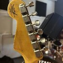 Záběr na zadní stranu hlavy kytary z přírodního dřeva. Na dřevě je černý nápis Custom Shop, LIMITED EDITION a logo Fender. Jsou zde vidět šest kovový…