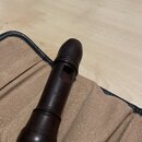 Tmavě hnědý dřevěný nástroj s vyfrézovaným otvorem, položený na béžové látkové výstelce v kufru. Na dřevě je viditelný nápis "Moeck". Povrch nástroje…