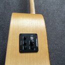 Detailní pohled na zadní stranu světlé dřevěné akustické kytary s instalovaným předzesilovačem. Černý ovládací panel nese nápisy FISHMAN, volume, tun…