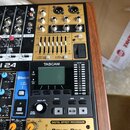 Detailní pohled na míchací pult s integrovaným digitálním procesorem a nahrávačem. Na zařízení je vidět značka TASCAM, označení modelu 24 a nápis DIG…