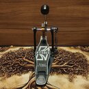 Fotografie zobrazuje černý bicí pedál s kovovou konstrukcí a bílými detaily. Na stupni je umístěno bílé logo TAMA s nápisem The Legend in Innovation.…