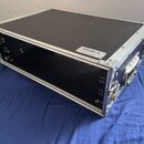 Černý transportní flightcase s hliníkovými hranami a rohy. Na horní hraně je bílá nálepka s nápisem PROEL a drobným textem pod ním. Case má na boku k…