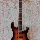 Elektrická kytara s hnědým gradientním povrchem a tmavým hmatníkem. Na hlavě je bílý nápis Ibanez. Nástroj má dva snímače typu humbucker, jeden poten…