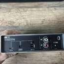 Zadní strana stříbrného USB audio rozhraní s černým panelem. Na zařízení jsou nápisy UR12, USB AUDIO INTERFACE, 24-bit/192kHz D-PRE, POWER SOURCE, US…