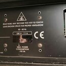 Detail zadní strany černého elektronického zařízení s nápisy a varovnými symboly. Je zde vidět napájecí konektor, pojistka s nápisem MAINS FUSE a tex…