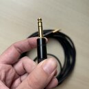 Černý instrumentální kabel s pozlaceným 6,3mm jack konektorem. Na černém plastovém pouzdře konektoru je viditelný nápis REAN. Kabel je sbalený do kro…
