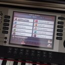 Detailní záběr na displej elektronického klavíru. Na obrazovce je zobrazeno menu s názvem VOICE (MAIN) a seznamy presetů, mezi nimiž jsou položky jak…