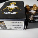 Černý efekt pedál s nápisem PANDORA a logem bílé postavy v žlutém trojúhelníku. Pedál má čtyři zlaté oválné knoflíky a dva stříbrné spínače s nápisy…