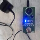 Zelený efekt pedál s nápisy DRUM MACHINE a FLAMMA. Obsahuje jeden ovládací knoflík s označením RHYTHM, dva modré přepínače LEVEL a EQ/SPEED, svítící…