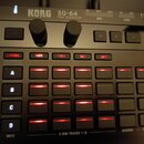 Černý sekvencer s nápisy KORG a SQ-64 POLY SEQUENCER. Zařízení obsahuje dva černé oválné knoflíky s popisky TEMPO a SWING, několik ovládacích tlačíte…